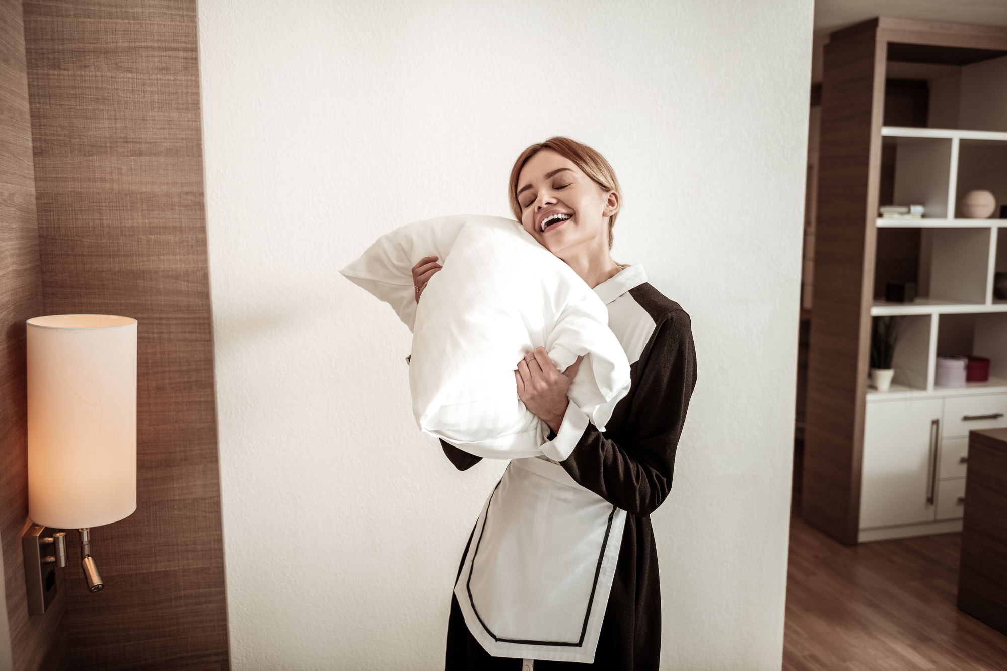 Dreaming of sleep. Young smiling experienced housekeeper dreaming of sleep while working