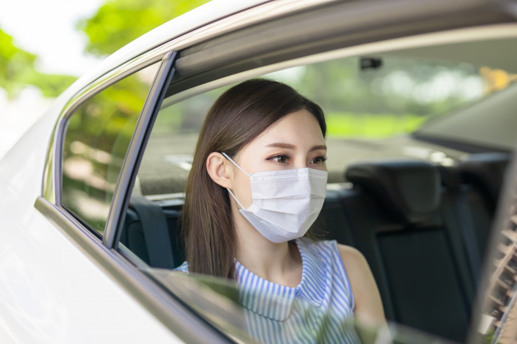 asian business woman commute by taxi and she wear face mask to avoid infectious diseases coronavirus